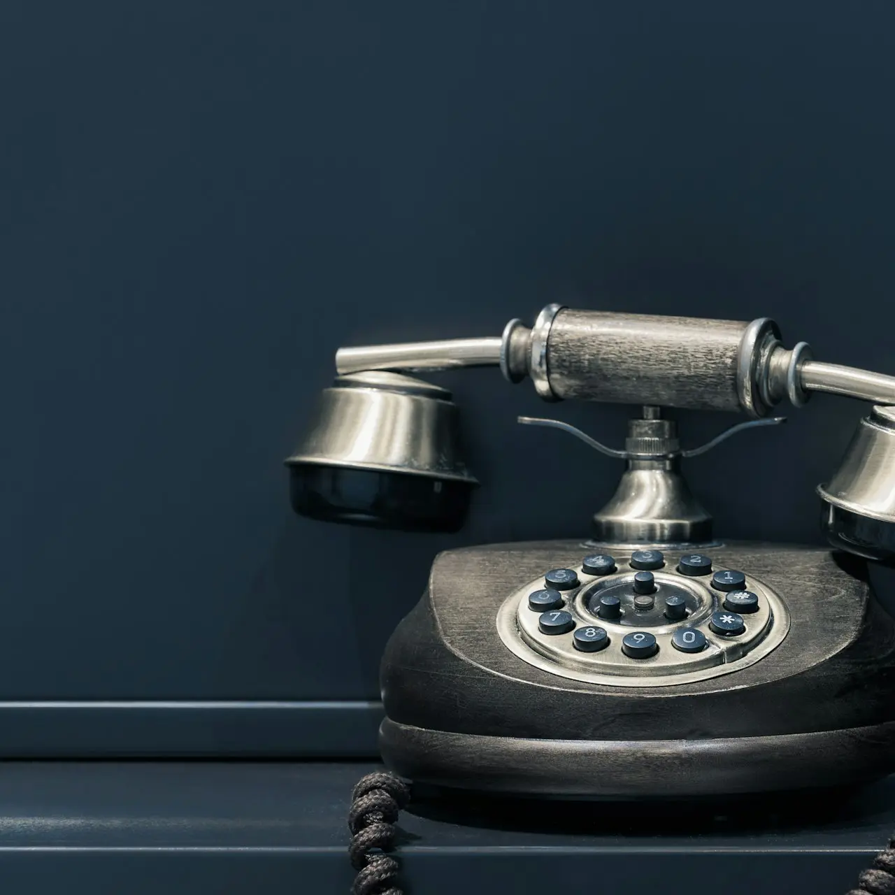 black and brown rotary phone near gray wall